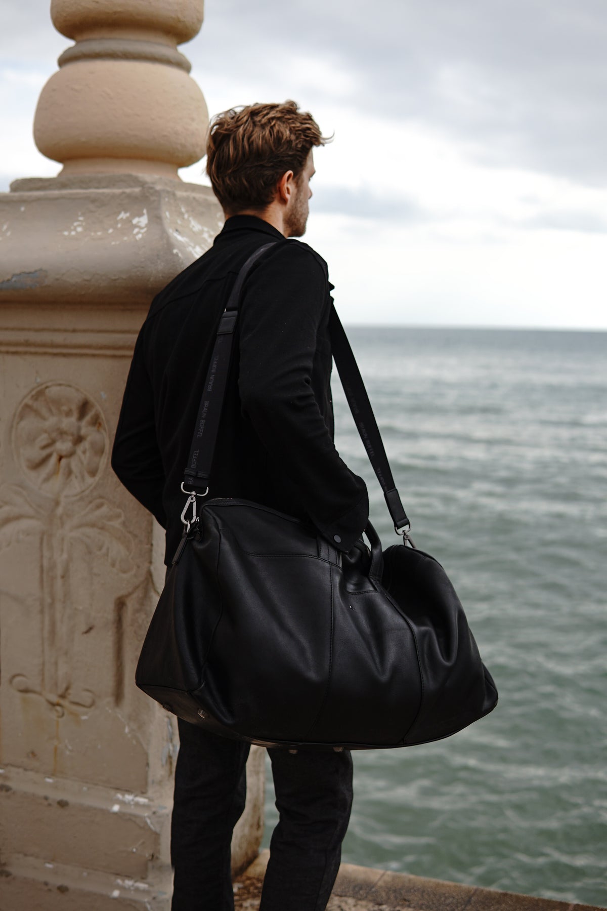 Mann trägt schwarze Ledertasche
