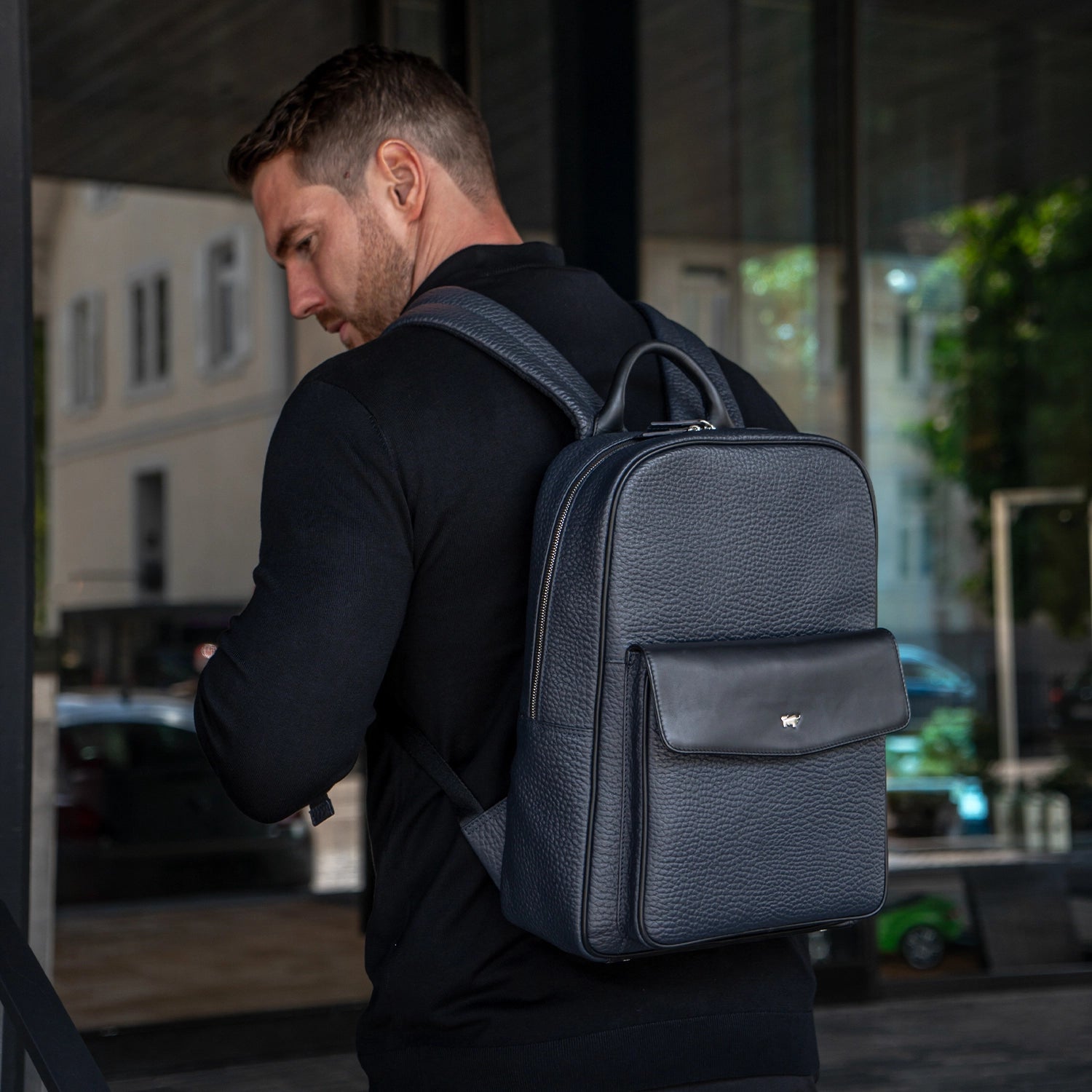 Mann mit dunkelblauem Rucksack aus Leder im Business Casual Look