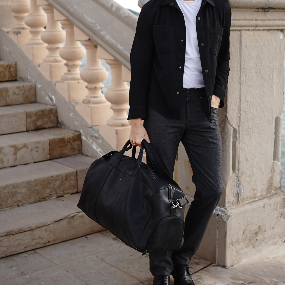 Mann mit schwarzer Reisetasche aus Leder im Smart Casual Look