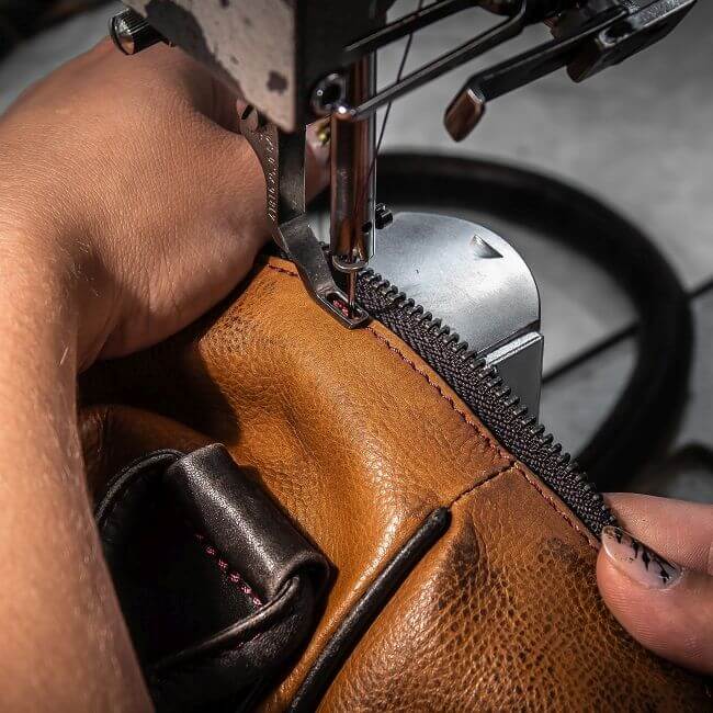 Frau repariert eine Tasche mit der Nähmaschine 